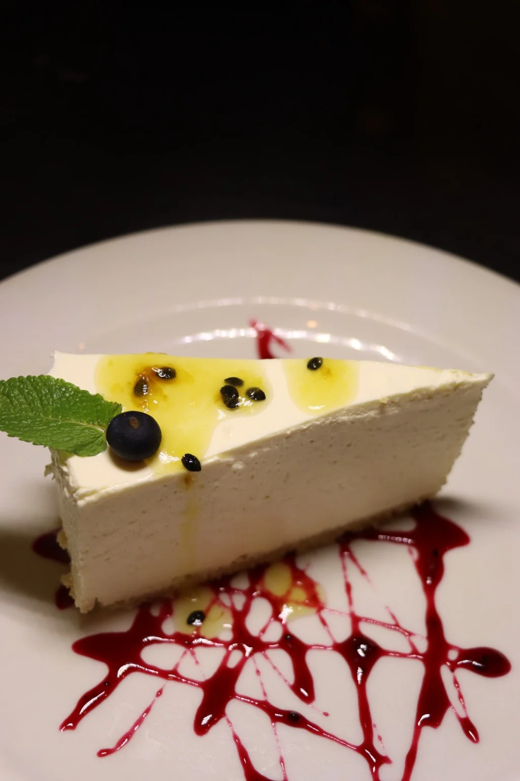 A slice of cheesecake with passion fruit and berry sauce