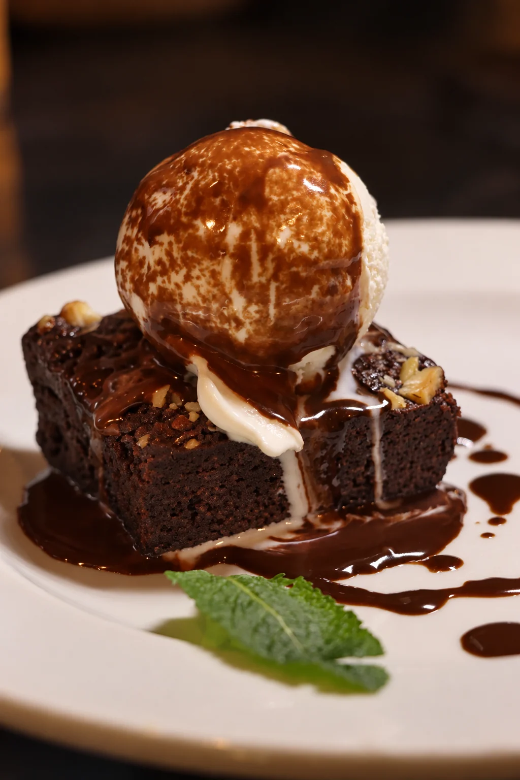 Chocolate brownie topped with ice cream and chocolate sauce, with fresh mint
